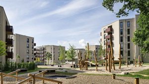 Ein moderner Spielplatz mit Holzstrukturen und Sand, umgeben von modernen Wohngebäuden und grünen Bäumen.